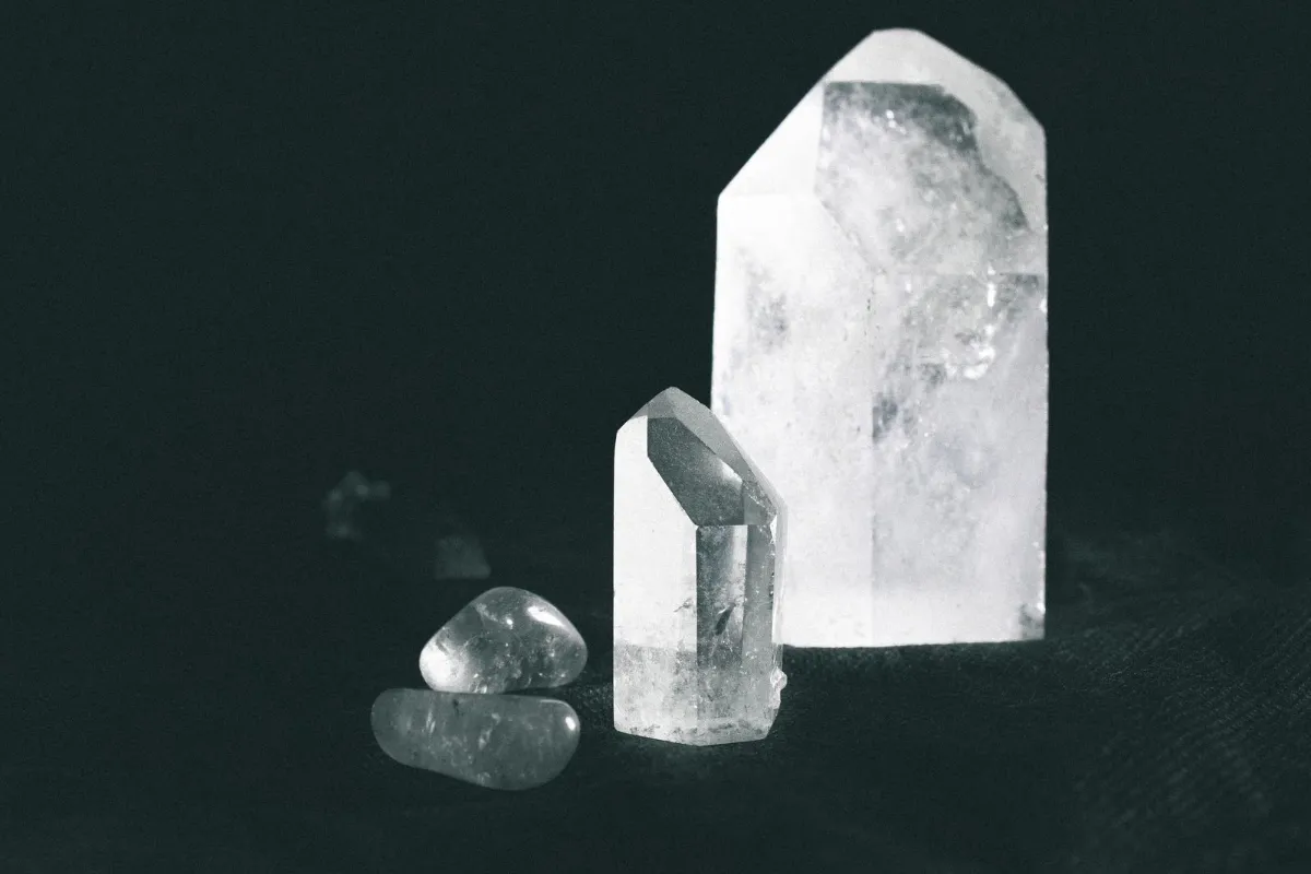 Clear quartz crystals, hardness 7 on the Mohs scale, on a dark surface